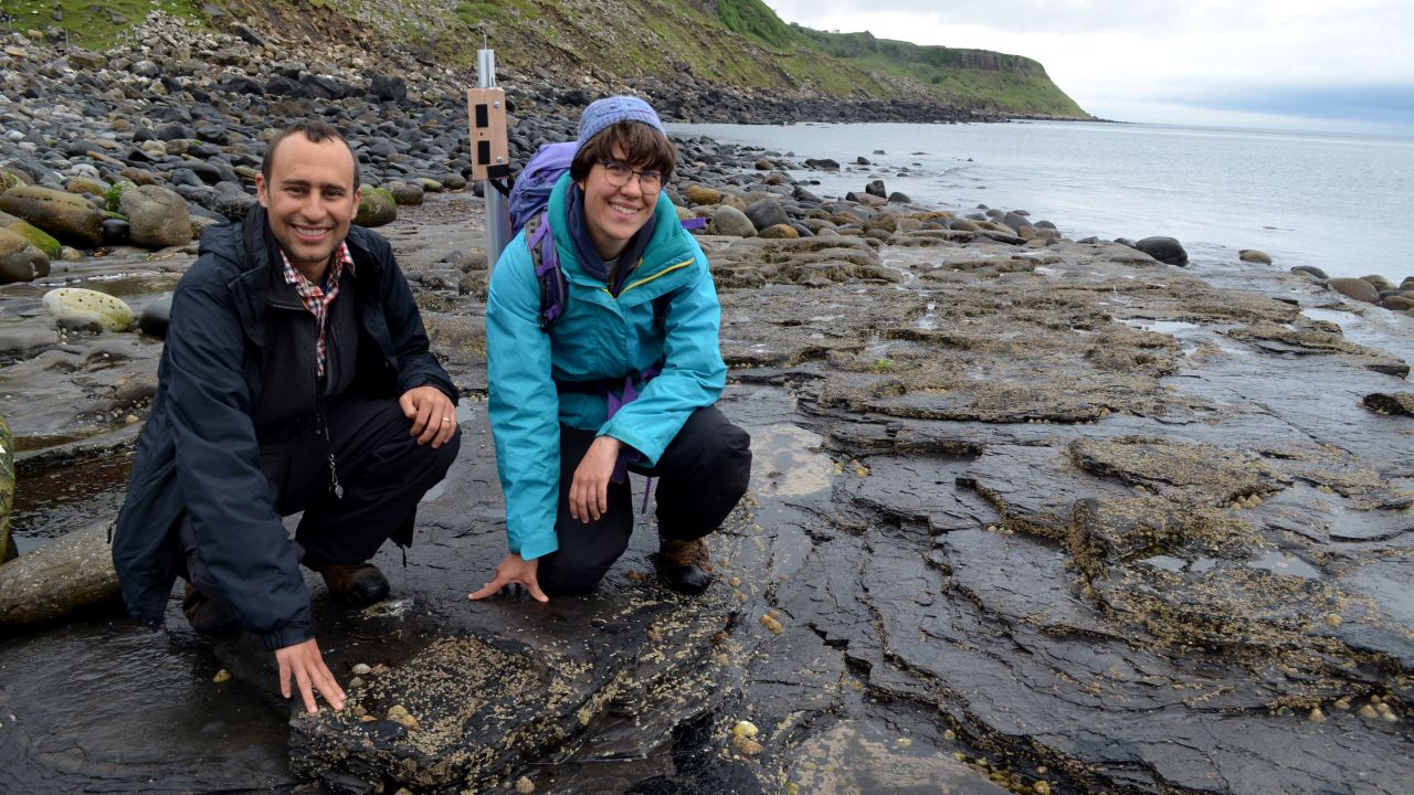 Steve Brusatte and Paige dePolo pose with fossil dinosaur tracks on the Isle of Skye.