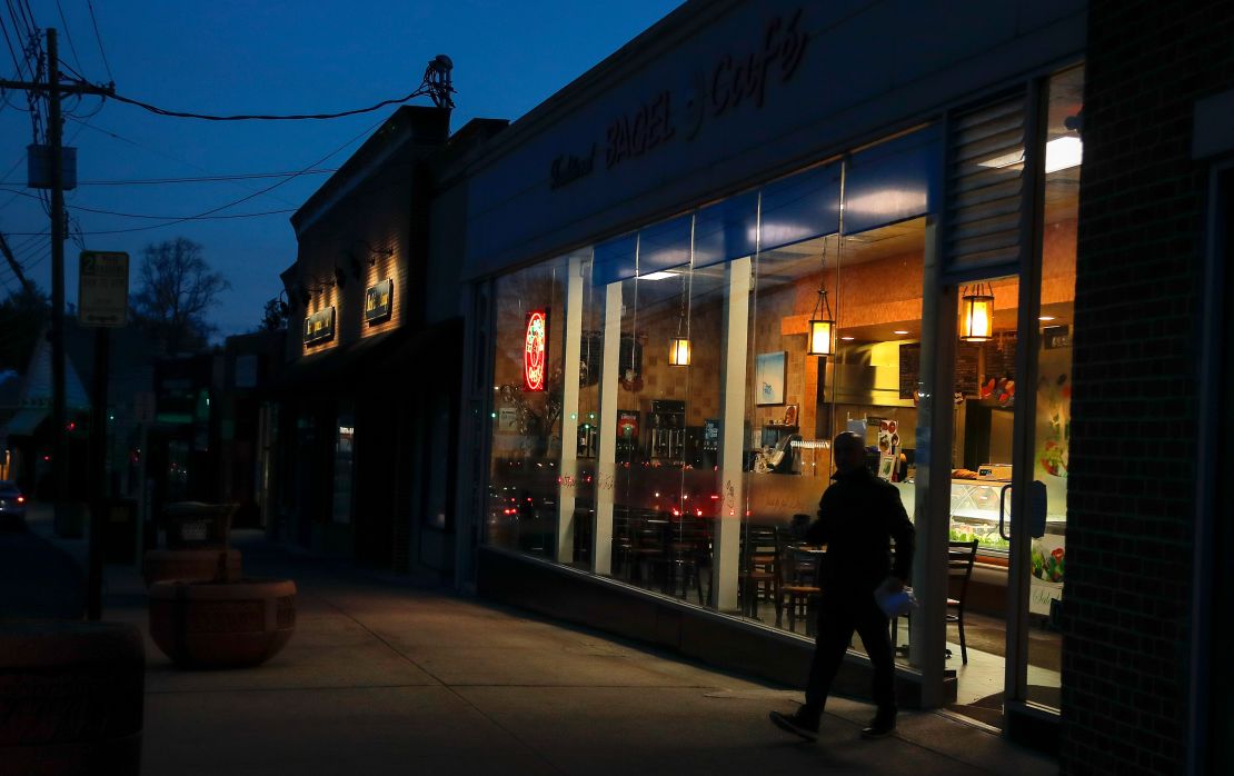 A customer walks out of a bagel shop after picking up coffee and a breakfast sandwich early Wednesday, March 11, 2020, in New Rochelle, New York.