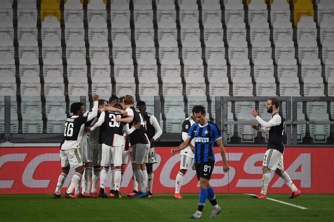 Juventus players celebrate after scoring against Inter Milan in an empty stadium. 