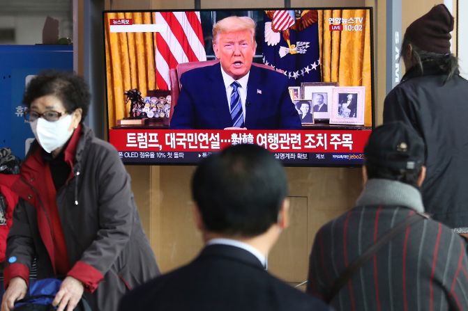 People at a railway station in Seoul, South Korea, watch a live broadcast of US President Donald Trump on March 12, 2020. Trump announced that, in an effort to slow the spread of the coronavirus, he would <a href="index.php?page=&url=https%3A%2F%2Fwww.cnn.com%2F2020%2F03%2F11%2Fpolitics%2Fdonald-trump-coronavirus-statement%2Findex.html" target="_blank">sharply restrict travel</a> from more than two dozen European countries.