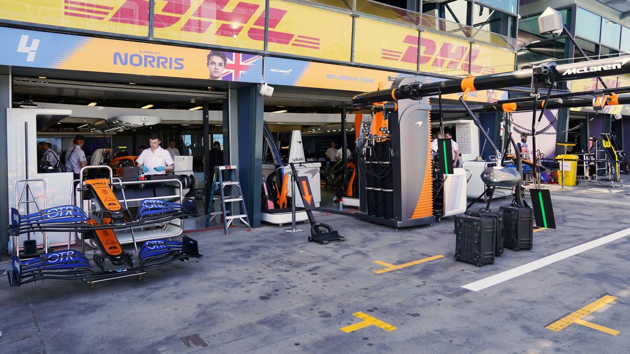 Technicians work around equipment and car parts in the The McLaren team pit at the Australian Formula One Grand Prix.