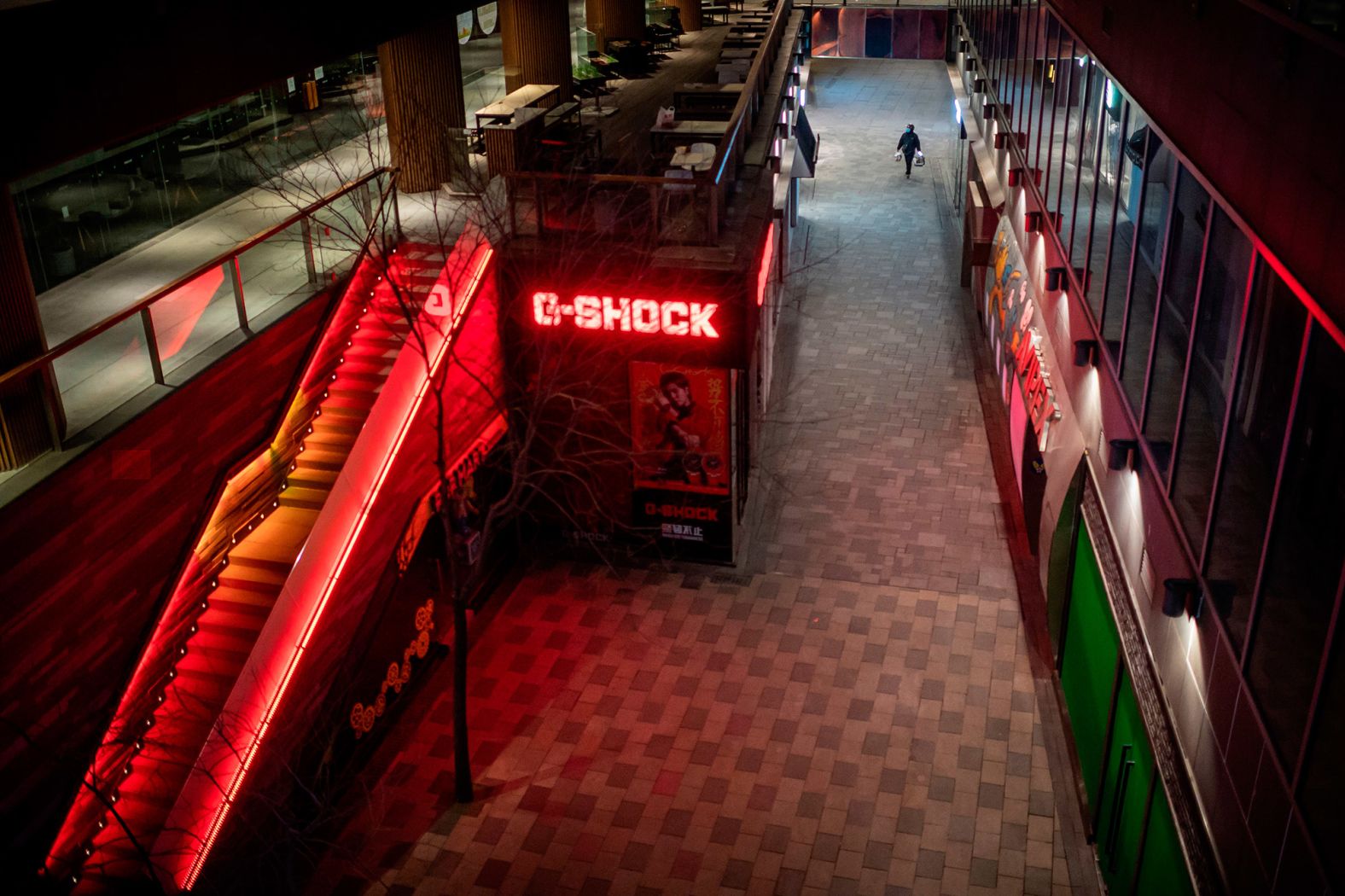 A delivery worker wearing a face mask walks at a nearly empty shopping mall in Beijing on February 27.