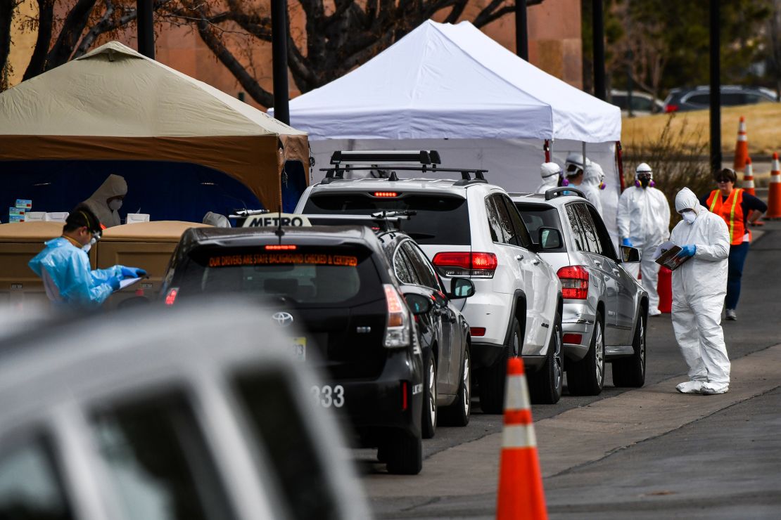 Health care workers from the Colorado Department of Public Health and Environment test people for Covid-19 on Thursday in Denver at the state's first drive-up testing center.