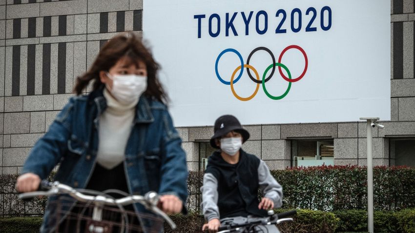 TOKYO, JAPAN - MARCH 13: People cycle past a banner for the Tokyo Olympics on March 13, 2020 in Tokyo, Japan. Excluding the Diamond Princess cruise ship cases, the number of coronavirus infections in Japan reached 684 today as United States President Donald Trump suggested the Tokyo Olympics should be postponed to next year. (Photo by Carl Court/Getty Images)