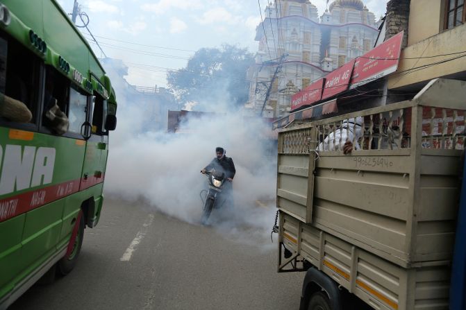 A motorcyclist drives through disinfectant sprayed in Jammu, India, on March 13, 2020.