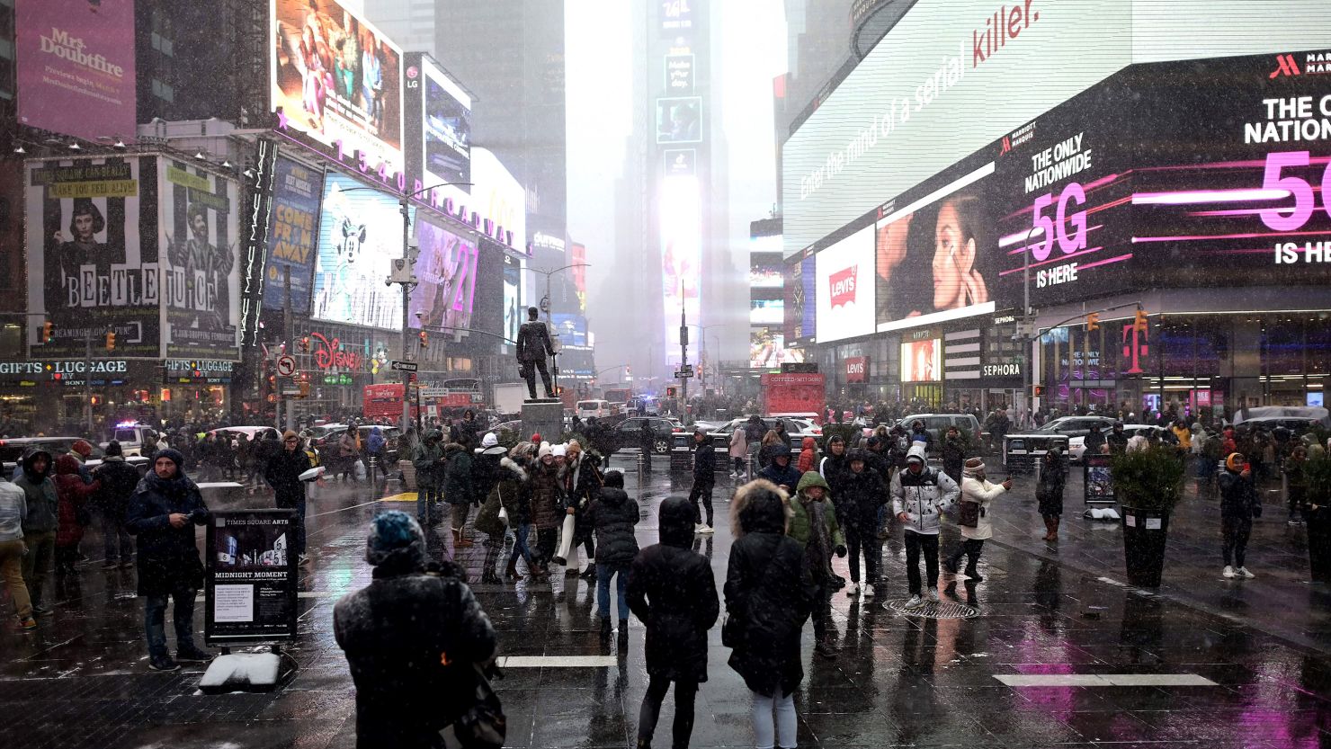 People take pictures during snowfall at Times Square on January 18, 2020.