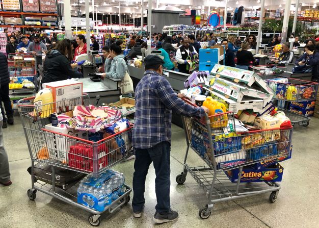 A Costco customer stands by two shopping carts in Richmond, California, on March 13, 2020.