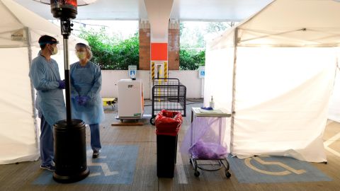 Nurses at a drive-up coronavirus testing station set up by the University of Washington Medical Center wear protective gear as they wait under a heater next to a tent Friday, March 13, 2020, in Seattle.