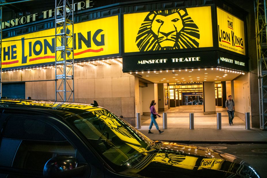 People walk past a closed Broadway theater after New York canceled all gatherings over 500 people.