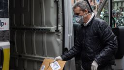 A courier, wearing a respiratory mask, handles an Amazon parcel on March 11, 2020 in Milan, Italy. The Italian Government has strengthened up its quarantine rules, shutting all commercial activities except for pharmacies, food shops, gas stations, tobacco stores and news kiosks in a bid to stop the spread of the novel coronavirus. 
