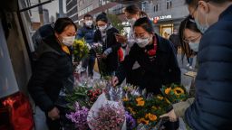 People wear protective masks as they buy flowers from the back of a van outside a shopping area on March 14, 2020 in Beijing, China. The number of cases of the deadly new coronavirus COVID-19 being treated in China dropped to below 15,000 in mainland China Friday, in what the World Health Organization (WHO) declared a global public health emergency last month. China continued to lock down the city of Wuhan, the epicentre of the virus, in an effort to contain the spread of the pneumonia-like disease but has moved to ease restrictions in other parts of the province. Officials in Beijing have put in place a mandatory 14 day quarantine for all people returning to the capital from other places in China and abroad. The number of those who have died from the virus in China climbed to over 3173 on Friday, mostly in Hubei province, and cases have been reported in many other countries including the United States, Canada, Australia, Japan, South Korea, India, Iran, Italy, the United Kingdom, Germany, France and several others. The World Health Organization declared it a pandemic earlier in the week and cases rose sharply in countries outside China. 