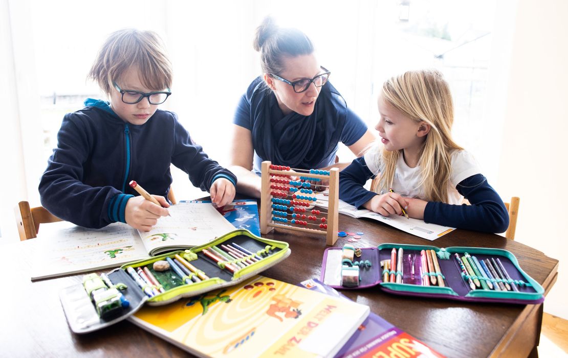 A mother helps her nine-year-old son and six-year-old daughter to do school homework on March 15, 2020 in Dinslaken, Germany.