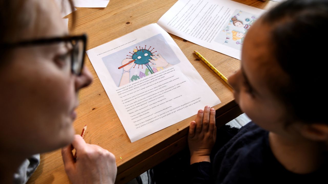 A mother helps her 5-year-old child to do school homeworks on the COVID-19 coronavirus on March 12, 2020 in Manta, near Cuneo, Northwestern Italy, as Italy shut all stores except for pharmacies and food shops in a desperate bid to halt the spread of a coronavirus that has killed 827 in the the country in just over two weeks.