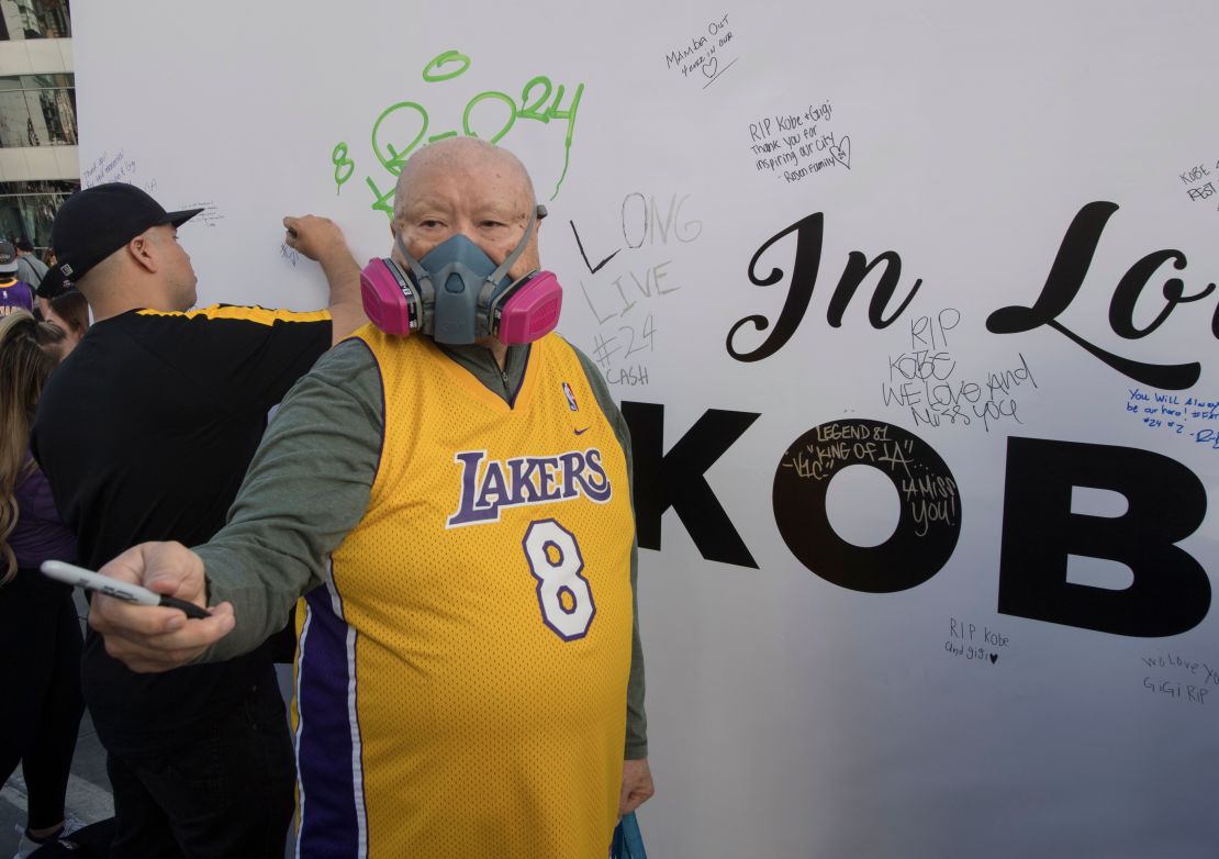 A Lakers fan wears a mask to protect against the Coronavirus as he pays his respects at a Staples Center memorial wall to NBA legend Kobe Bryant,