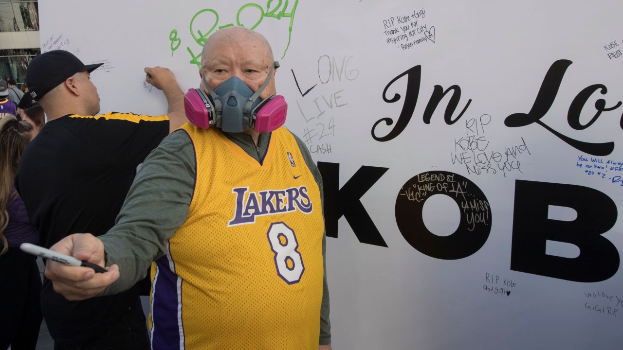 A Lakers fan wears a mask to protect against the Coronavirus as he pays his respects at a Staples Center memorial wall to NBA legend Kobe Bryant,