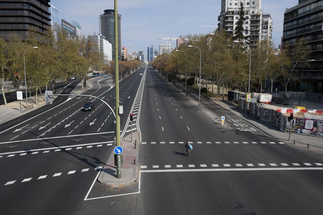 A woman crosses the usually busy La Castellana avenue in Madrid on March 15, 2020.