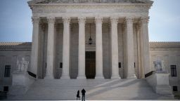 Two people stand at the base of the U.S. Supreme Court on March 16, 2020 in Washington, DC. The Supreme Court announced on Monday that it would postpone oral arguments for its March session because of the coronavirus outbreak.