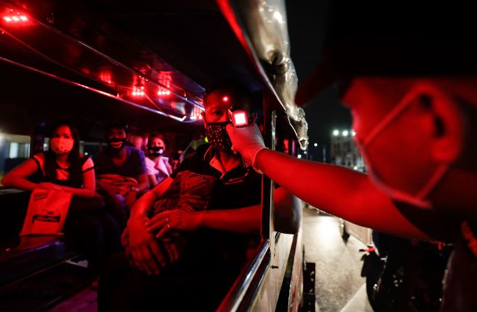 A police officer checks the temperatures of bus passengers at a checkpoint in Manila, Philippines.