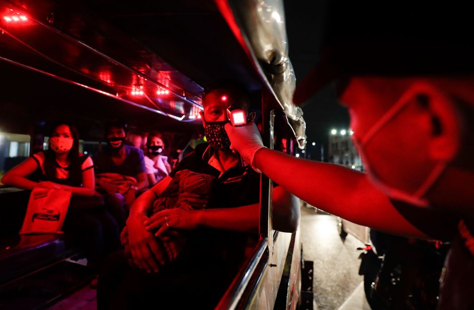 A police officer checks the temperatures of bus passengers at a checkpoint in Manila, Philippines, on March 16.