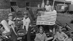circa 1943:  Full-length image of a group of boys posing on a heap of scrap metal during a victory drive in support of the US homefront effort during World War II. Three boys hold American flags as the others display pieces of metal. They wear 'Junior Corps' caps.  (Photo by Hulton Archive/Getty Images)