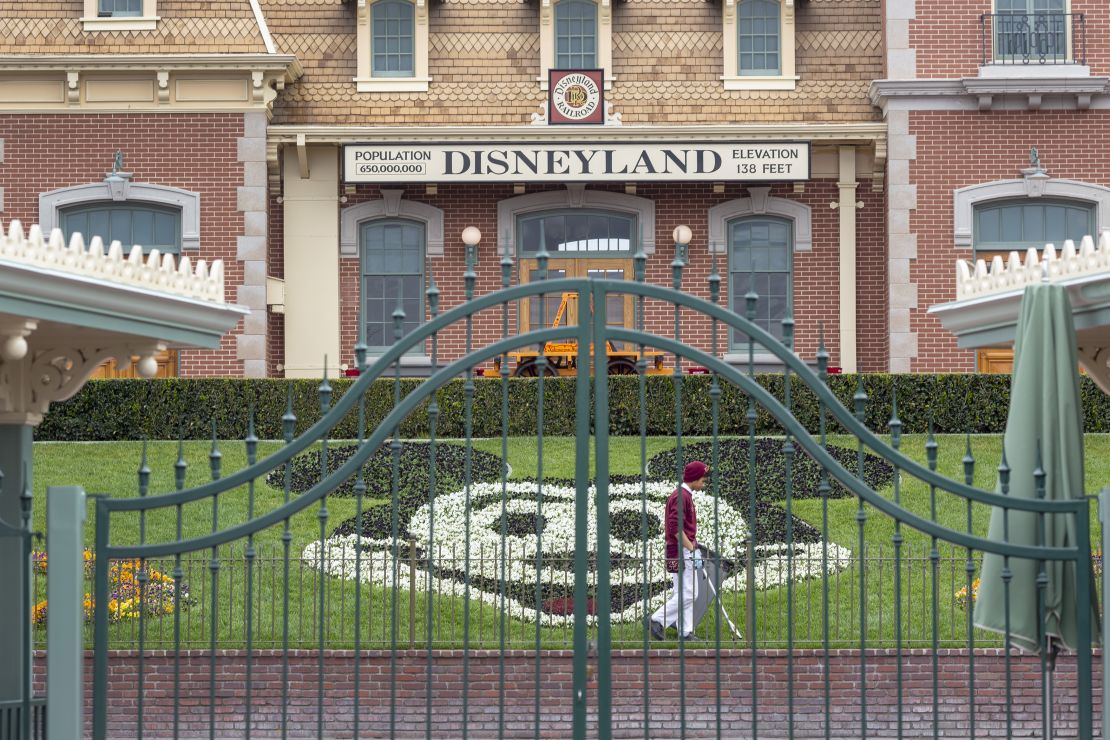 An employee cleans the grounds behind the closed gates of Disneyland Park back in March 2020.