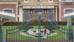 An employee cleans the grounds behind the closed gates of Disneyland Park on the first day of the closure of Disneyland and Disney California Adventure theme parks as fear of the spread of coronavirus continue, in Anaheim, California, on March 14, 2020. - The World Health Organization said March 13, 2020 it was not yet possible to say when the COVID-19 pandemic, which has killed more than 5,000 people worldwide, will peak. "It's impossible for us to say when this will peak globally," Maria Van Kerkhove, who heads the WHO's emerging diseases unit, told a virtual press conference, adding that "we hope that it is sooner rather than later". (Photo by DAVID MCNEW / AFP) (Photo by DAVID MCNEW/AFP via Getty Images)