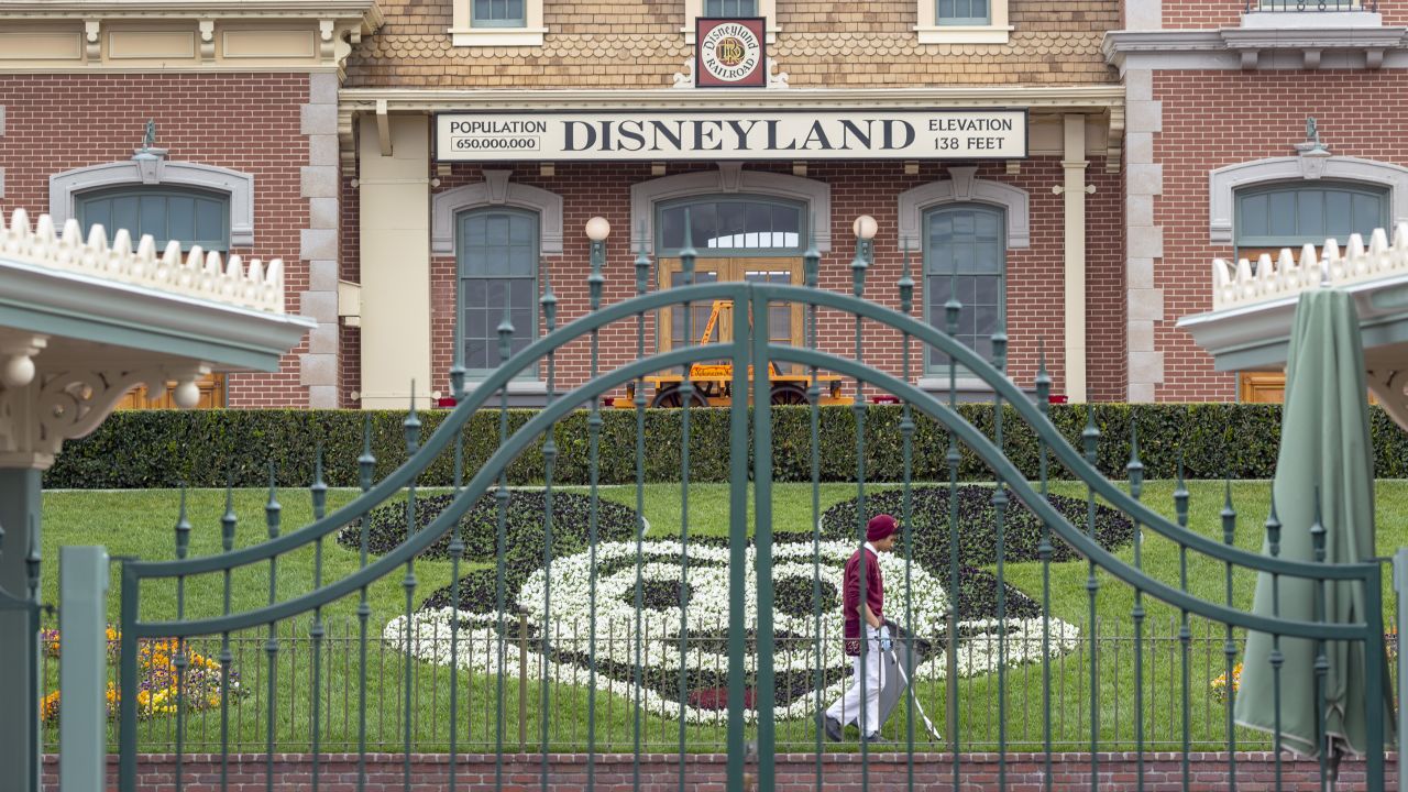 An employee cleans the grounds behind the closed gates of Disneyland Park back in March  2020.