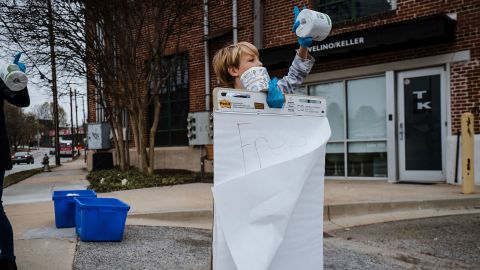 A volunteer holds up a sign that reads "Free Toilet Paper" in Trevelino/Keller's parking lot.