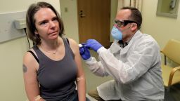 A pharmacist gives Jennifer Haller, left, the first shot in the first-stage safety study clinical trial of a potential vaccine for COVID-19, the disease caused by the new coronavirus, Monday, March 16, 2020, at the Kaiser Permanente Washington Health Research Institute in Seattle. (AP Photo/Ted S. Warren)