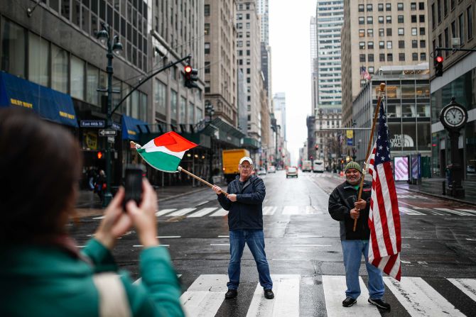 Dermot Hickey, left, and Phillip Vega ask a pedestrian in New York to take their picture on a thinly trafficked Fifth Avenue on March 17. Many streets across the world are much more bare as people distance themselves from others. In the United States, the White House has advised people <a href="https://trans.hiragana.jp/ruby/https://www.cnn.com/2020/03/16/politics/white-house-guidelines-coronavirus/index.html" target="_blank">not to gather in groups of more than 10.</a>