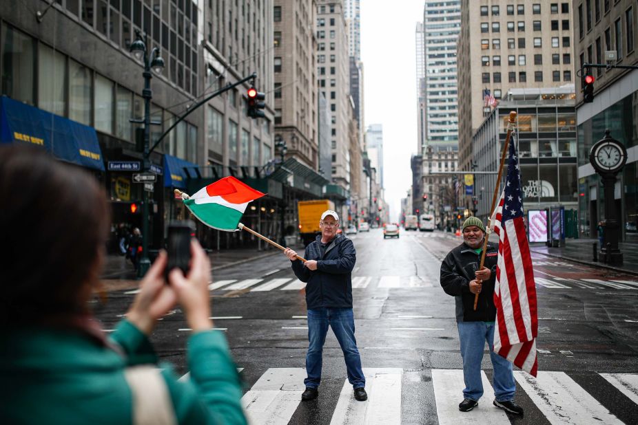 Dermot Hickey, left, and Phillip Vega ask a pedestrian in New York to take their picture on a thinly trafficked Fifth Avenue on March 17. Many streets across the world are much more bare as people distance themselves from others. In the United States, the White House has advised people <a href="https://www.cnn.com/2020/03/16/politics/white-house-guidelines-coronavirus/index.html" target="_blank">not to gather in groups of more than 10.</a>
