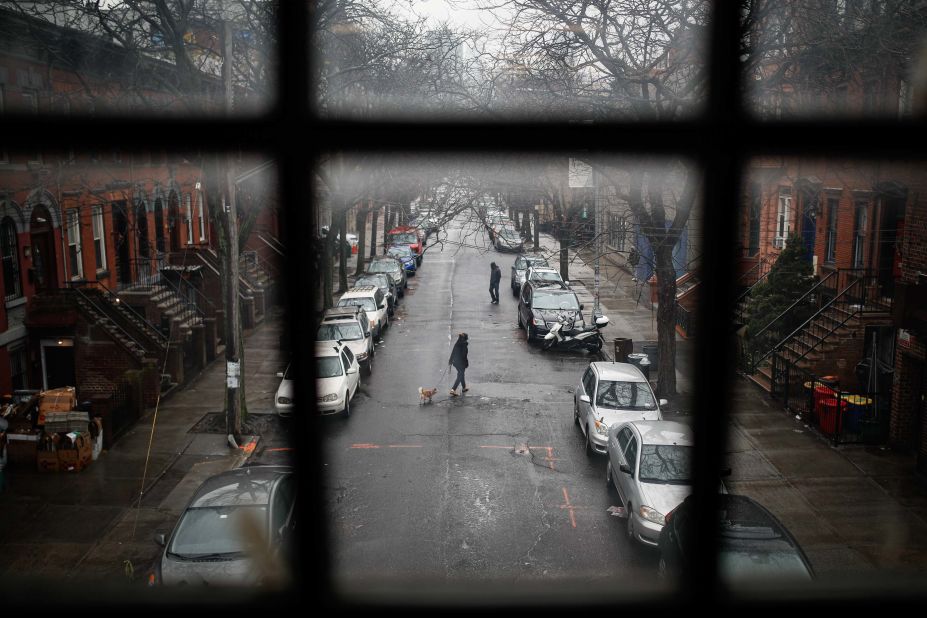 A pedestrian walks a dog through a quiet street in New York on March 17, 2020.