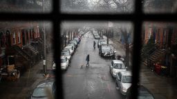 A pedestrian walks their dog through a quiet street, Tuesday, March 17, 2020, in the Brooklyn borough of New York. New York state entered a new phase in the coronavirus pandemic Monday, as New York City closed its public schools, and officials said schools statewide would close by Wednesday. New York joined with Connecticut and New Jersey to close bars, restaurants and movie theaters along with setting limits on social gatherings. (AP Photo/John Minchillo)