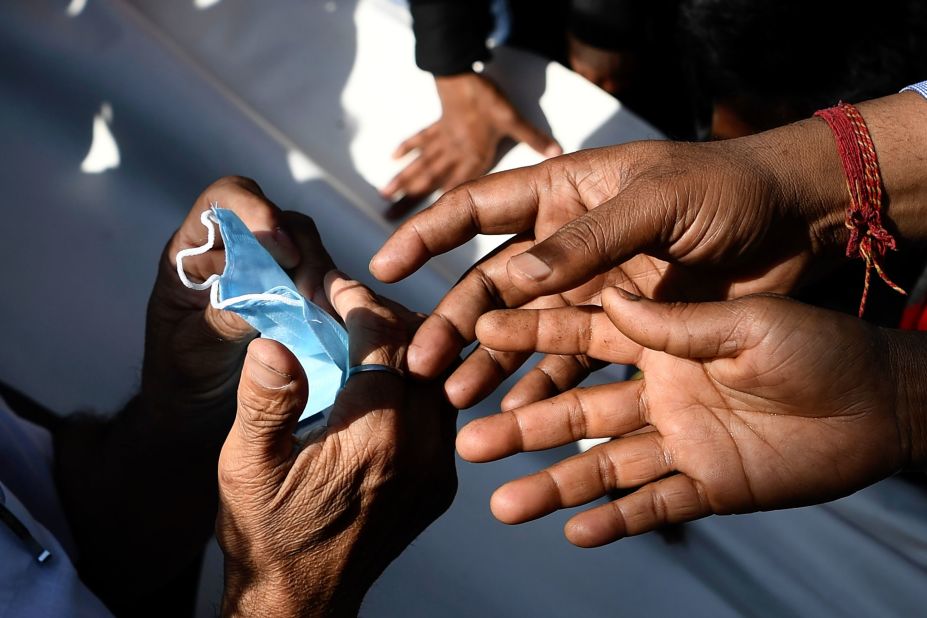 People gather to collect free face masks in New Delhi on March 17.