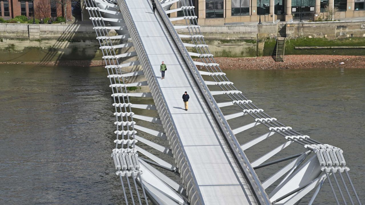 Pedestrians cross a quiet Millennium Footbridge across the River Thames in London on March 17.