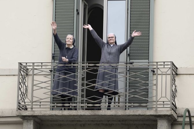 Two nuns greet neighbors from their balcony in Turin, Italy, on March 15, 2020.