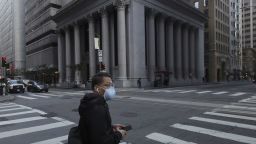 A man wearing a mask waits to cross an intersection in San Francisco, Tuesday, March 17, 2020. 