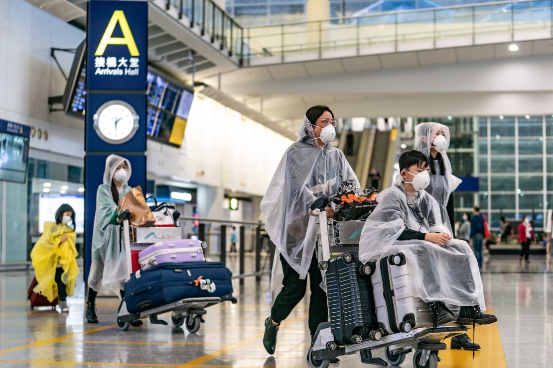 Travellers wearing protective equipment enter the arrival hall at the Hong Kong International Airport on March 17, 2020 in Hong Kong.