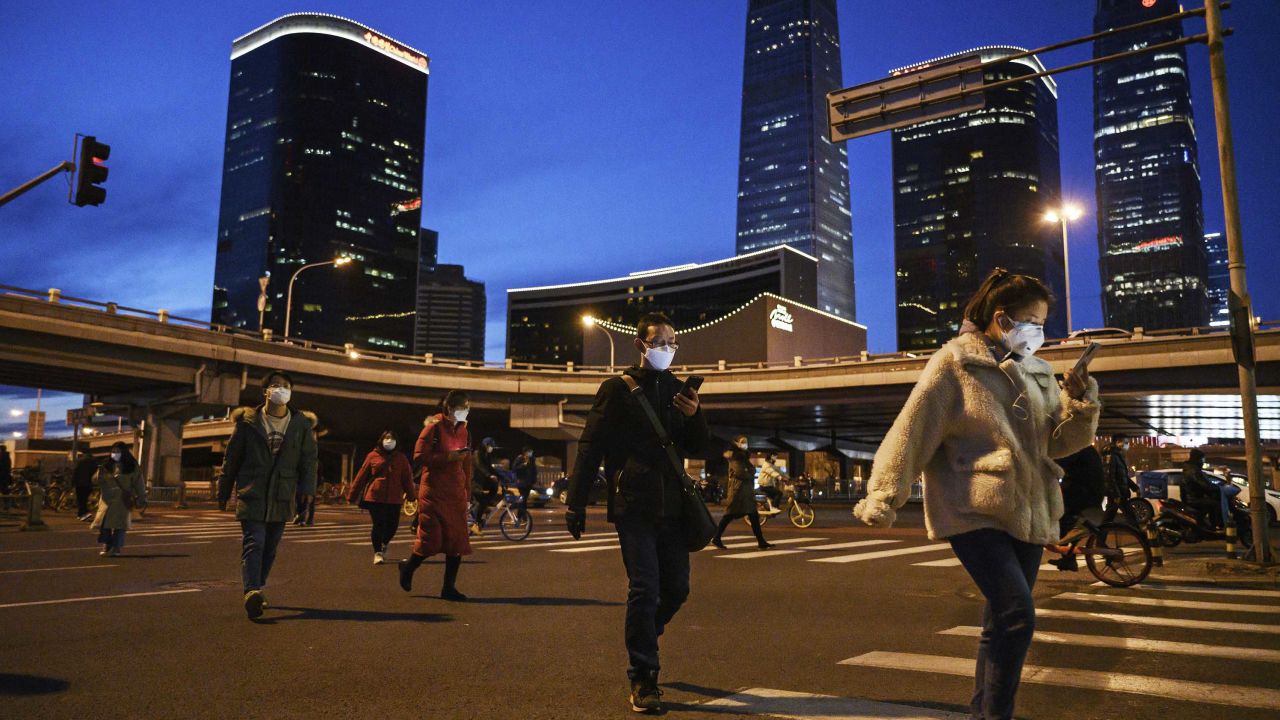 Chinese office workers wear protective masks as they cross a road during rush hour in the central business district  on March 12, 2020 in Beijing.