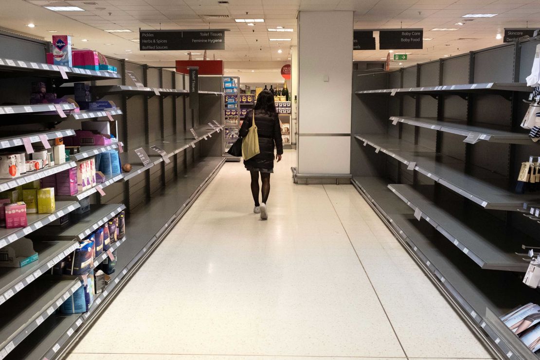 A customer walks past empty shelves in a Waitrose supermarket in London.