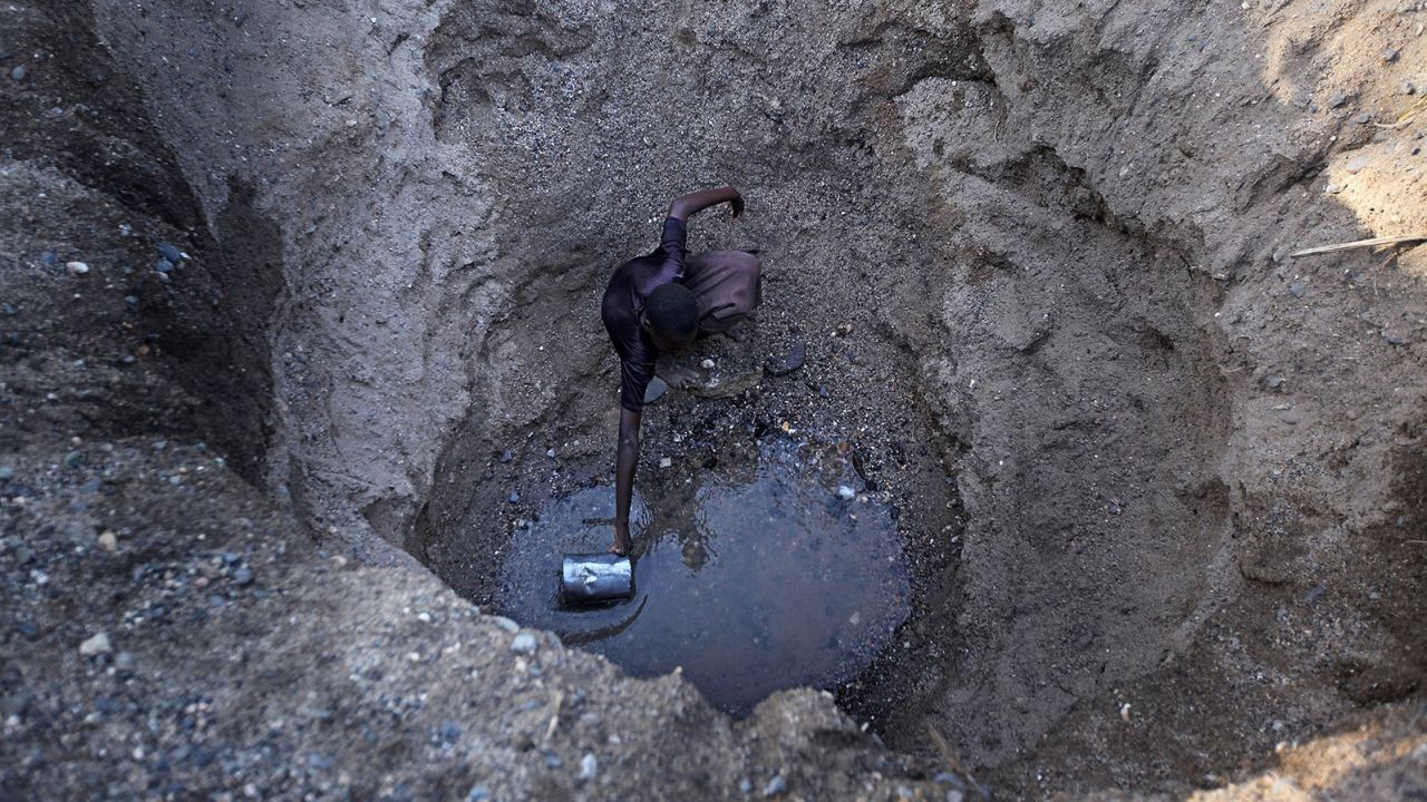 Children from the remote Turkana tribe in Northern Kenya dig a hole in a river bed to retrieve water.