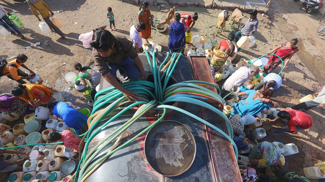 Indian slum dwellers collect potable water from a municipal water tanker in Durga Nagar.
