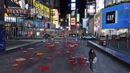 A woman walks through a lightly trafficked Times Square in New York, Monday, March 16, 2020. Bars and restaurants will become takeout-only and businesses from movie theaters and casinos to gyms and beyond will be shuttered Monday night throughout New York, New Jersey and Connecticut because of the coronavirus, the states' governors said. (AP Photo/Seth Wenig)