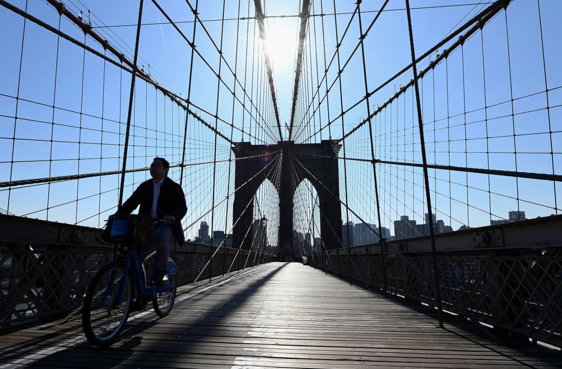 A person rides their bike over an empty Brooklyn Bridge.