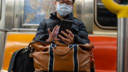 A passenger wearing a surgical mask uses his iPhone while riding an uptown subway in New York City on March 18, 2020. New York City subways are nearly empty with most businesses closed and people voluntarily sheltering due to the spreading of the Coronavirus. 
