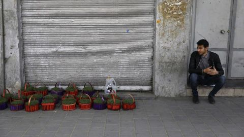 As coronavirus ravages businesses in Iran, a vendor sits next to his baskets of grass shoots ahead of Nowruz in front of closed shops at Tehran's Grand Bazaar. 