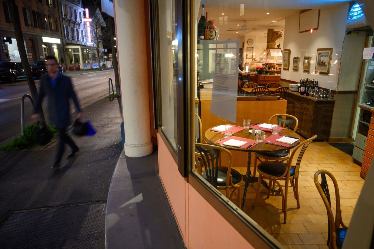 A man walks past an empty restaurant in Lausanne, Switzerland, on Friday, March 13.