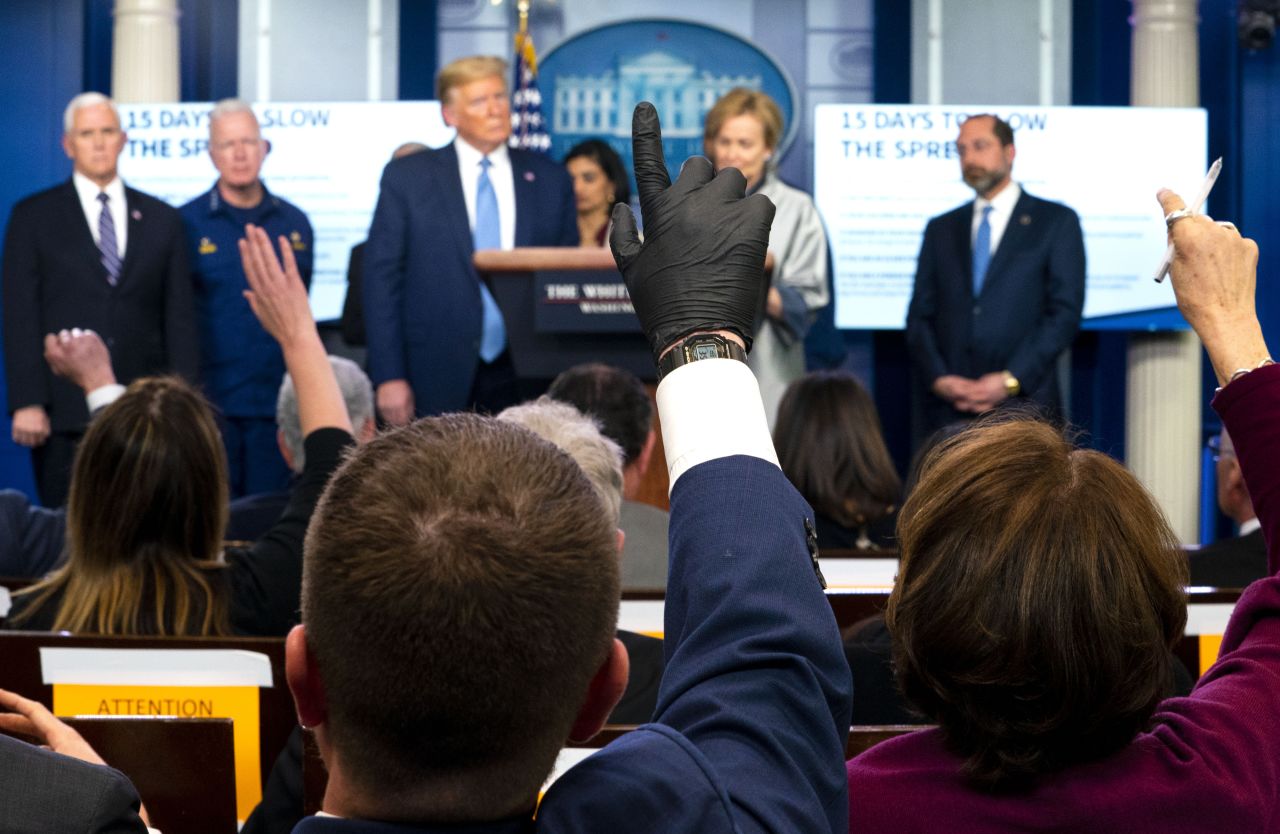 A reporter wears latex gloves as President Donald Trump takes questions in the White House briefing room on Monday, March 16.