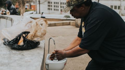 A man washes his hands in a portable wash station in Atlanta's Hurt Park.