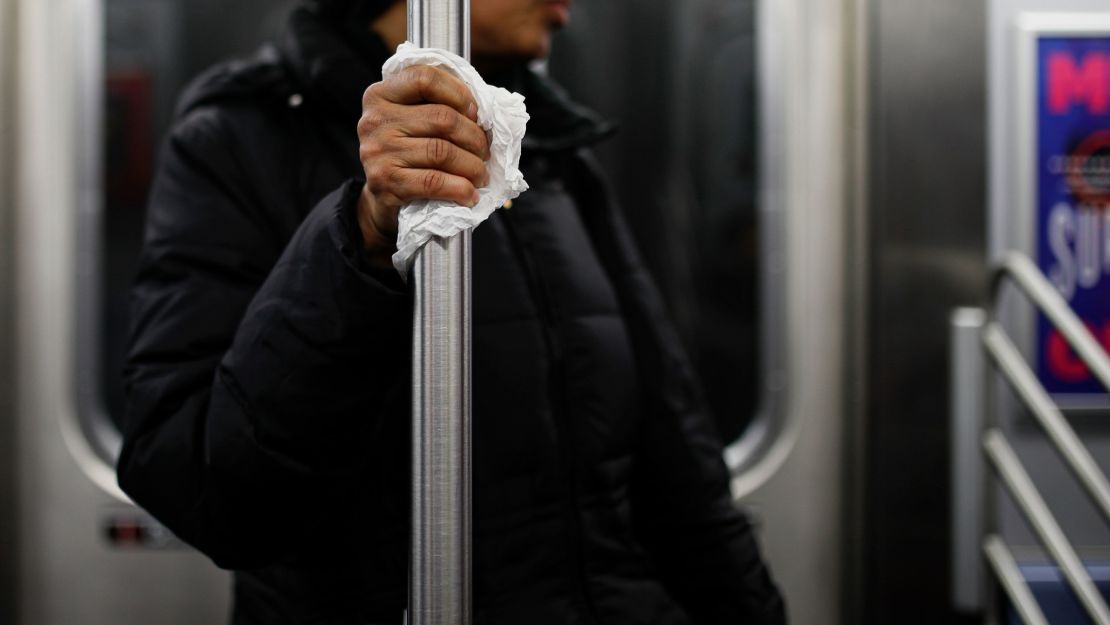 A subway customer uses a tissue to protect her hand while holding onto a pole  Thursday, March 19, in New York City. 